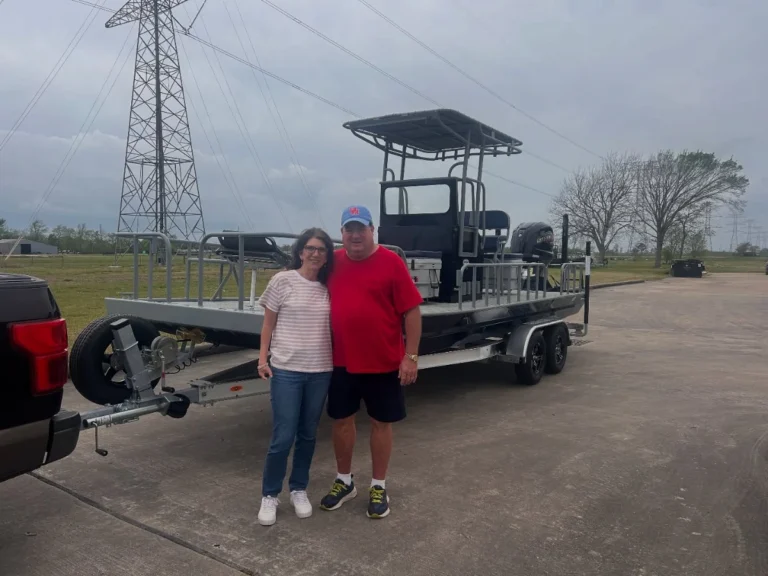 Two owners standing in front of their new gray Boat Right with a T-top