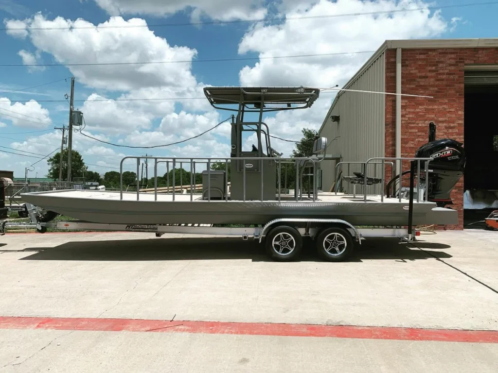 Gray Boat Right with a T-top on its trailer outside the shop, seen from the side