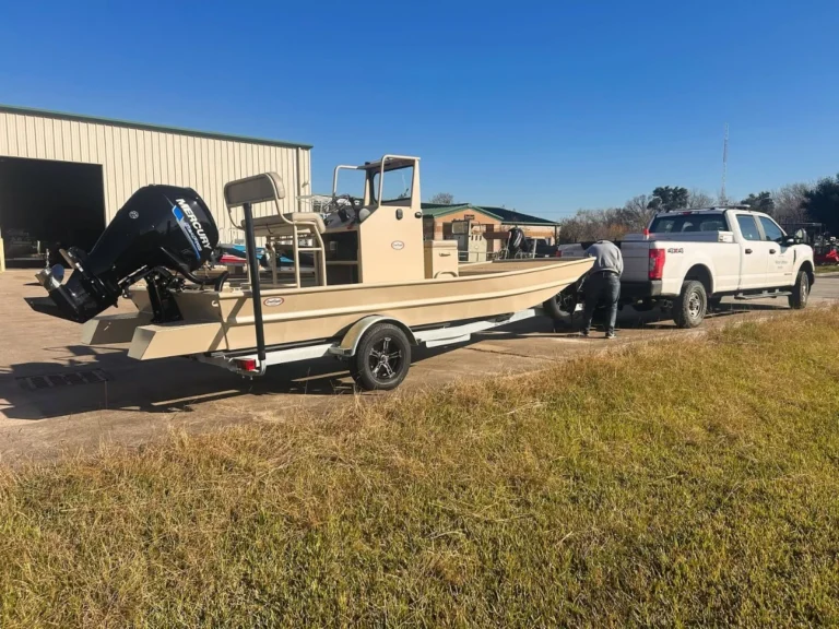 Tan Boat Right hitched behind a white pickup truck