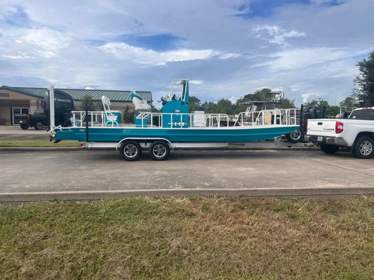 Teal Boat Right hitched behind a white pickup truck